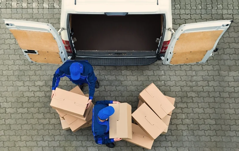 Aerial view of movers loading cardboard boxes into van.