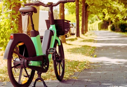 A light green electric bicycle parked on a sidewalk.