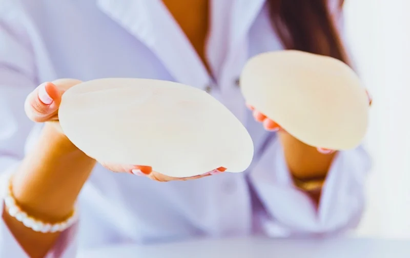 Breast Implants? This Article Could Save Your Life 1 A medical professional holding two round silicone breast implants.