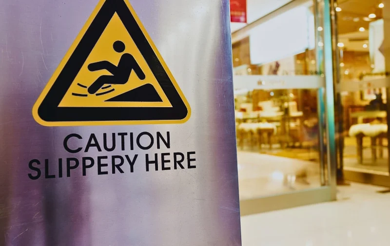 A yellow caution slippery sign inside a retail mall.