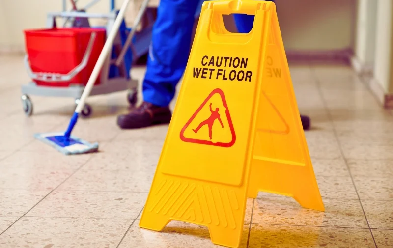 Yellow wet floor sign in front of cleaning cart.