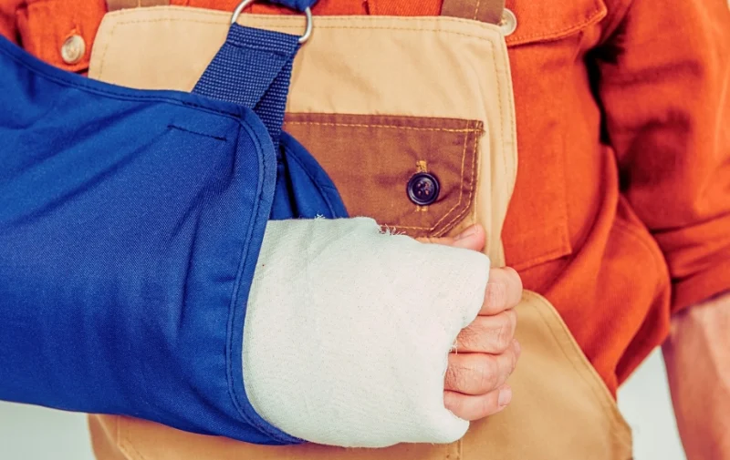 Close-up of a worker’s arm in a cast and sling.