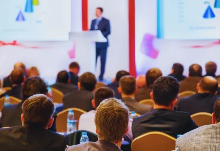 People sitting in an audience listening to a presenter.