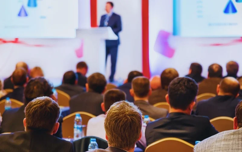 Injured at a Business Conference? Multiple Parties May Be Liable 1 People sitting in an audience listening to a presenter.