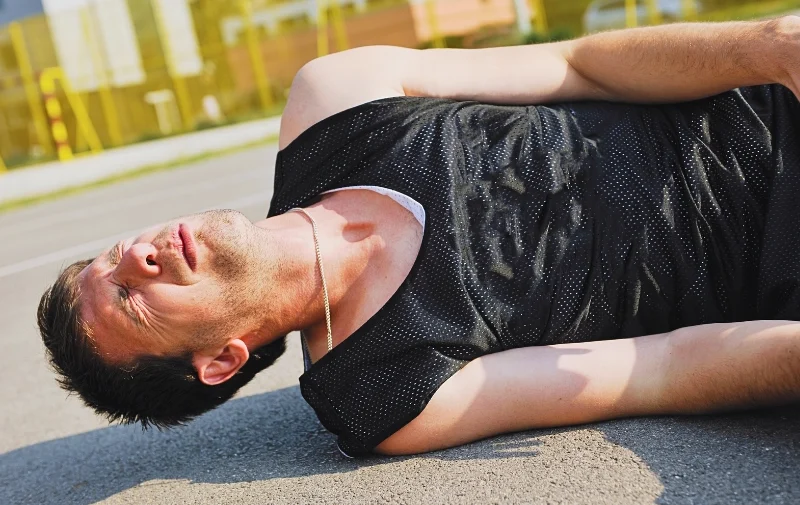 A man lying on the ground in visible pain.