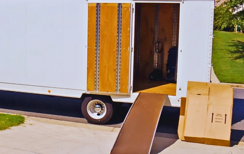 An open moving trailer with a ramp and boxes.