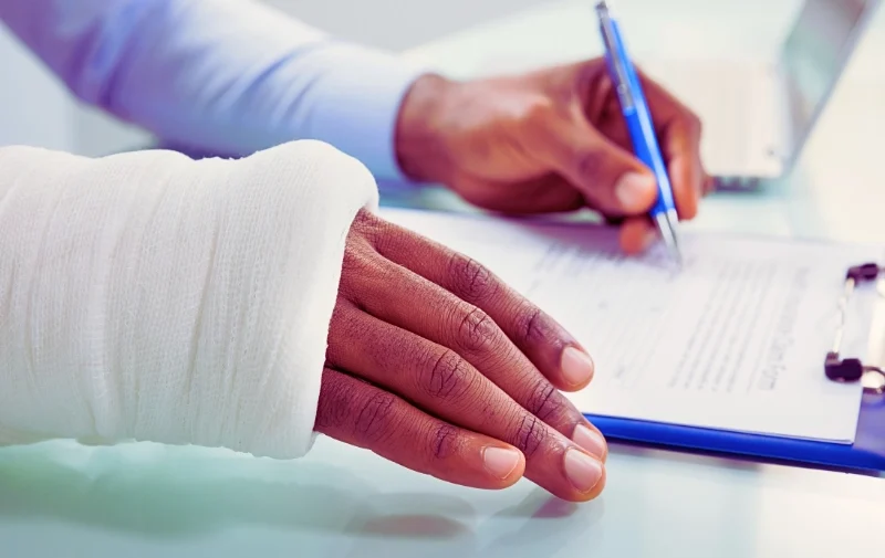 Injured hand in a white cast signs a document.
