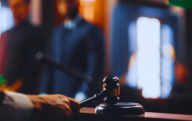 A hand strikes a gavel in a courtroom.