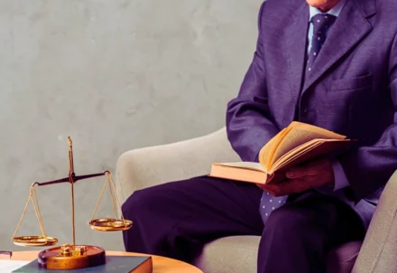 A lawyer reads a book next to justice scales.