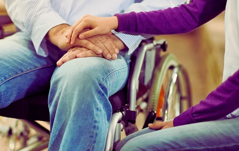 Why You Should Hire a Lawyer for Social Security Disability 1 A hand rests supportively on another person in a wheelchair.