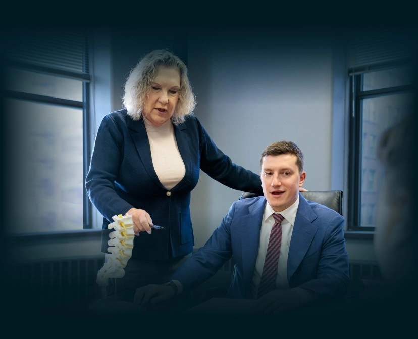 Chicago lawyers, Donna Zadeikis and Alexander Pino sitting in office examining a model of a human spinal column.