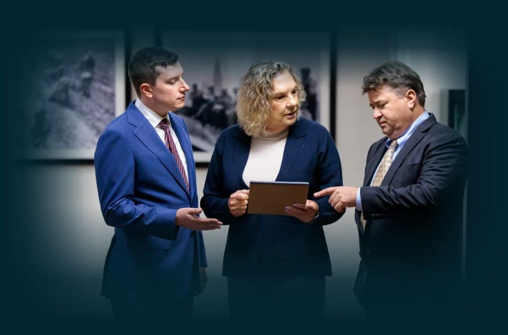 Chicago lawyers, John Serkland, Donna Zadeikis and Alexander Pino stand together discussing information shown on a tablet.