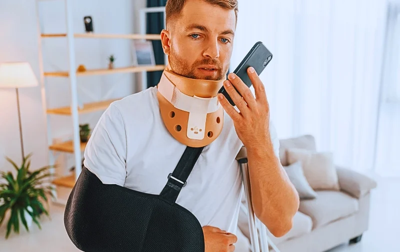 What to Do If Your Employer Accuses You of Faking a Work Injury 1 Man with injured arm and neck using his phone.