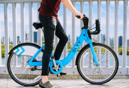 Person riding a blue Divvy bicycle in front of railing. injured while riding a Divvy bike